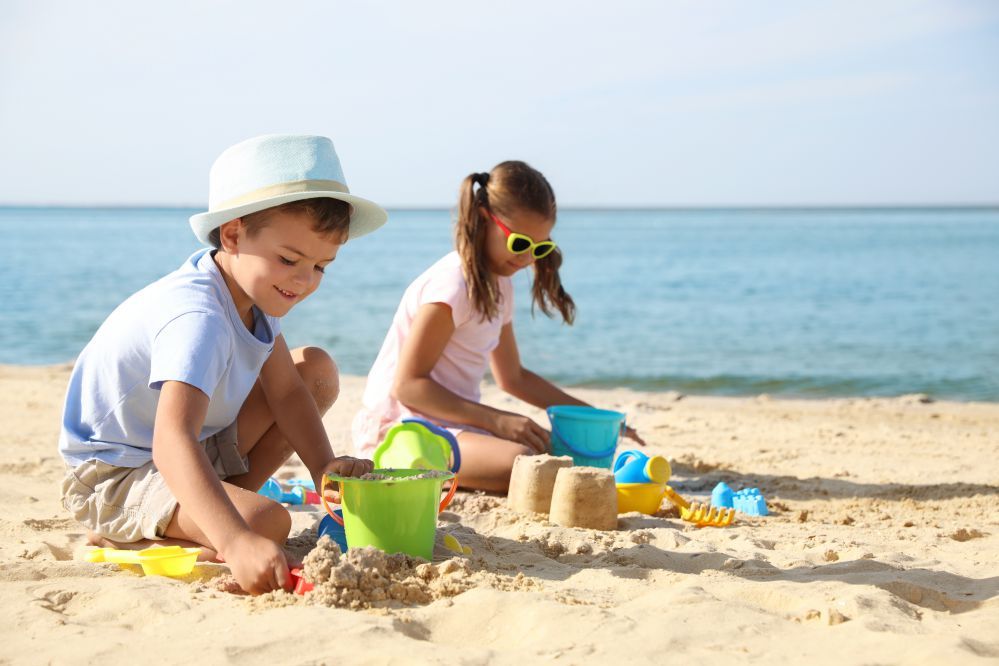 Un bambino e una bambina giocano con la sabbia sulla spiaggia in riva al mare